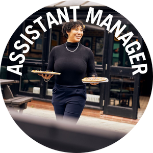 Assistant Manager takes food to outside table. Banner reads 'Assistant Manager'