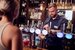 A man standing behind a bar, pulling a pint of beer for a woman.