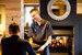 man in a restaurant handing a menu to a guest sat at a table