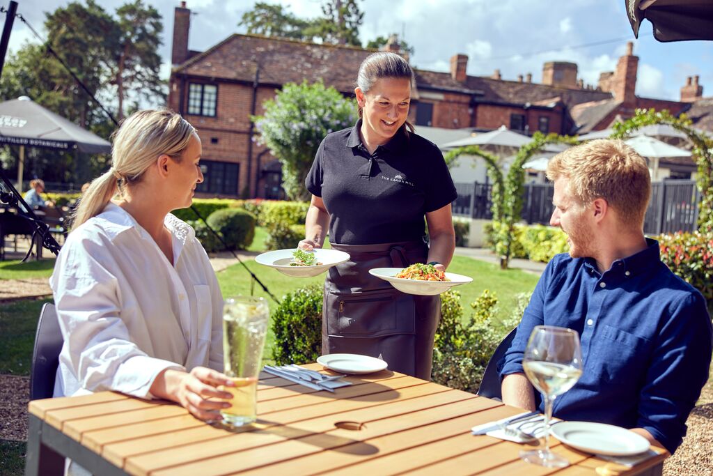 Waitress bringing food to the couple by the table