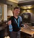 keith pictured in a pub holding an award and a bottle of alcohol