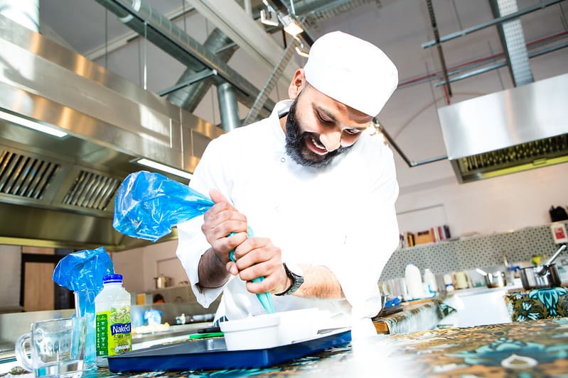 Male chef piping into porcelain dish, learning how to become a chef at mitchells and butlers