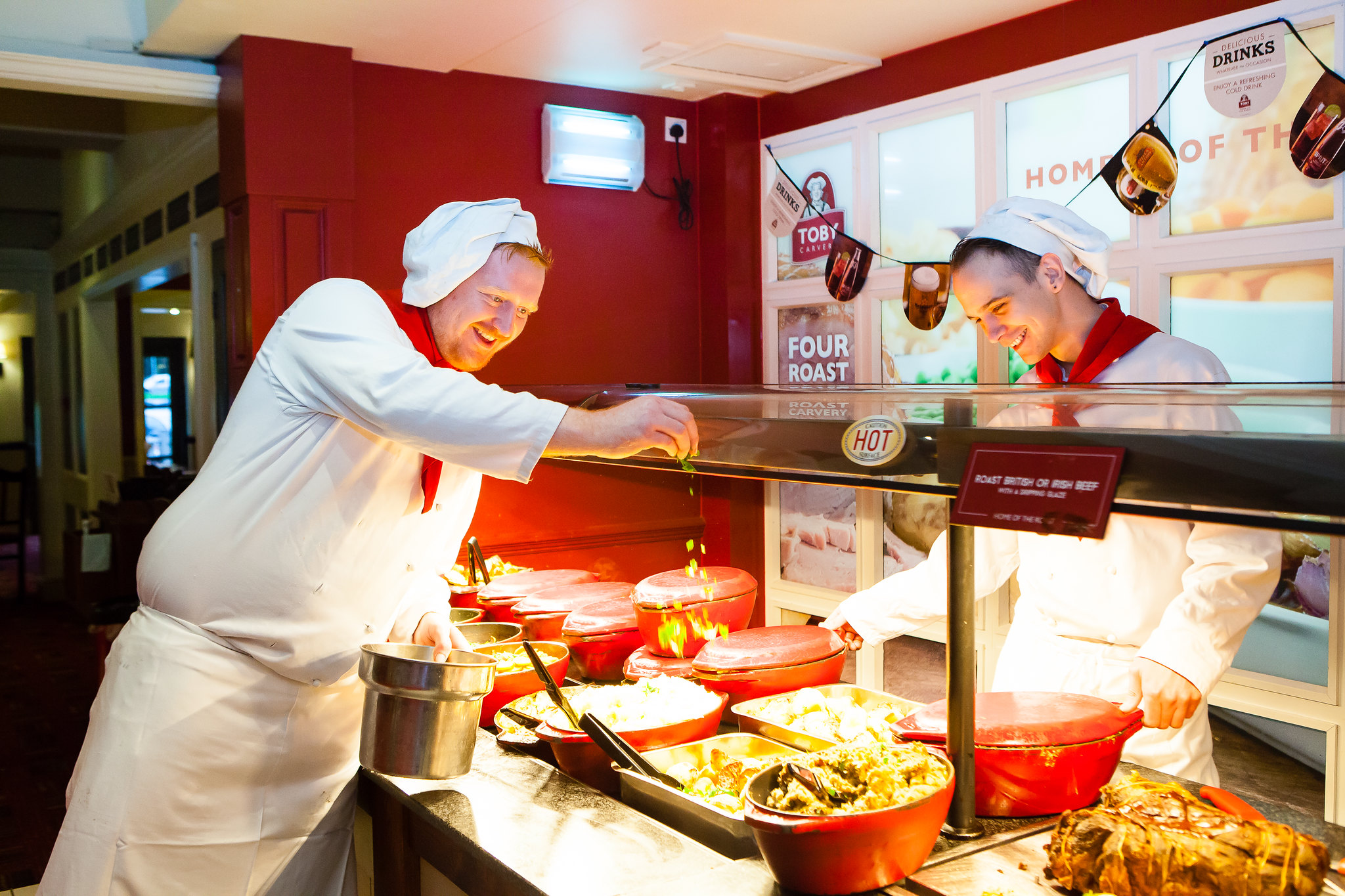 two men wearing chef's whites cooking in a commercial kitchen