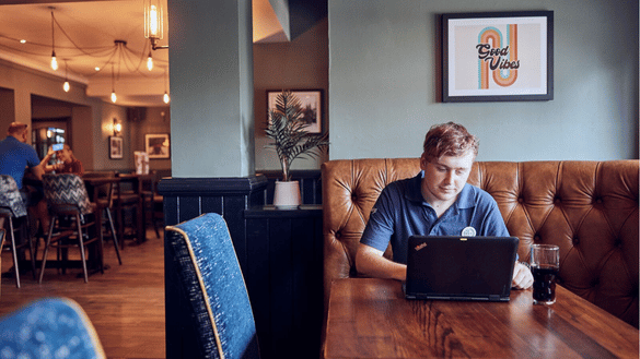 A team member in a sizzling pub completes training on the laptop