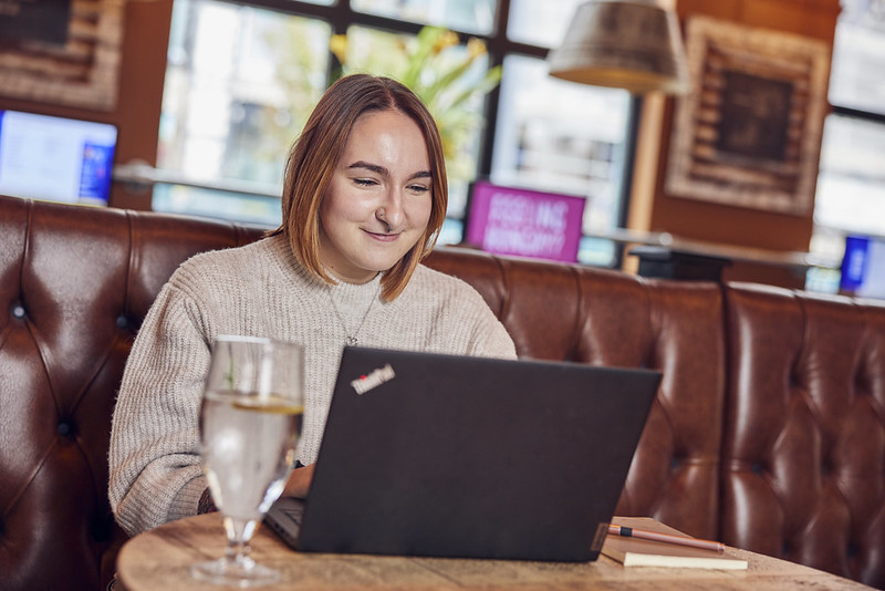 smiling lady on laptop sitting at pub 