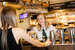 two girls standing at a restaurant bar laughing