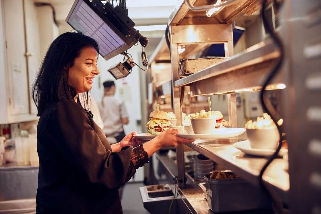 chef handing plates to general manager in a commercial kitchen