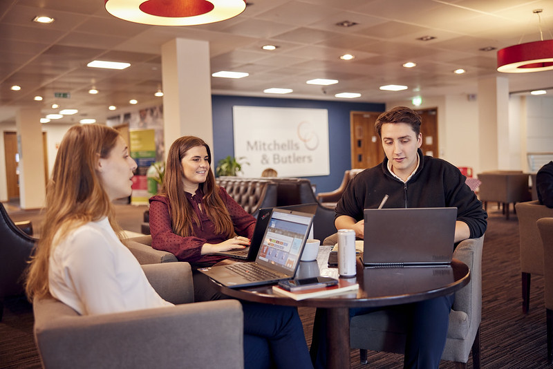 three people sitting at a line of computers laughing