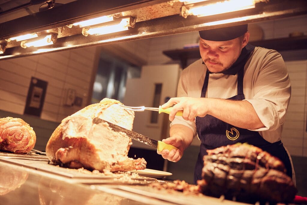 image of chef carving meat in the kitchen