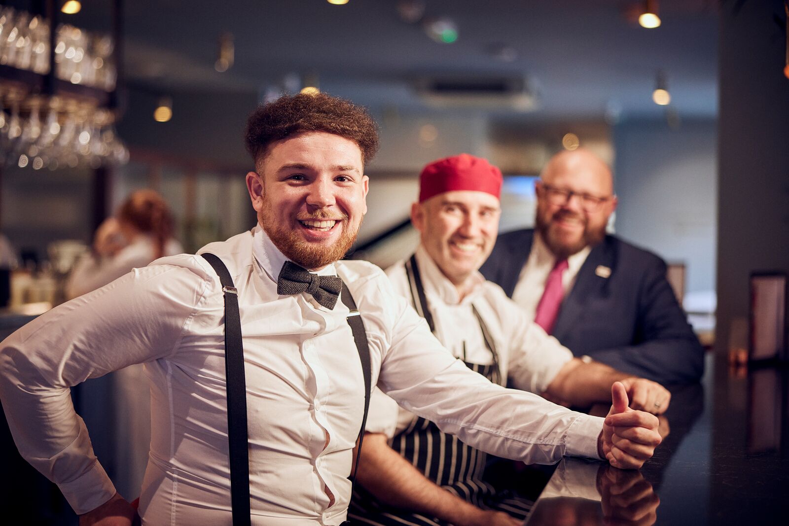 three m&B employees posing for a photo behind the bar