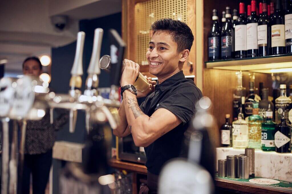 bar staff making a cocktail behind the bar