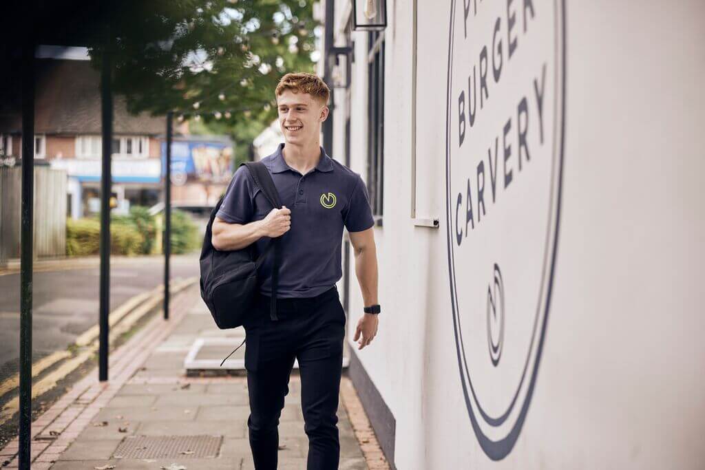 image of M&B employee walking outside of a pub smiling 