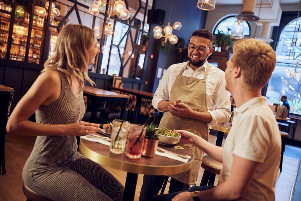 image of bar staff smiling at customers whilst delivering food 