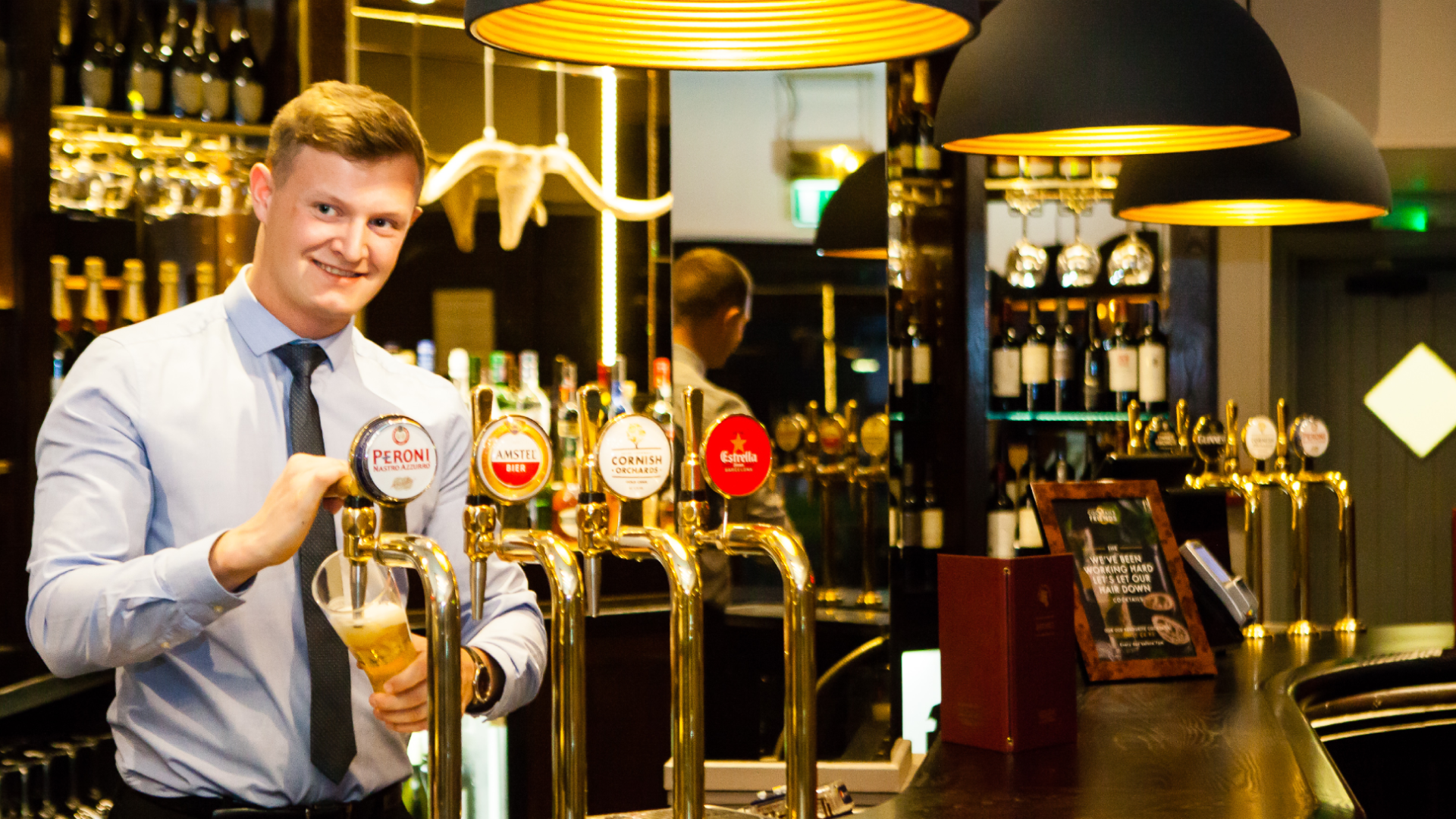 Smiling bar staff pouring a pint, working in hospitality