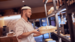 man in chef whites passing plated food to a woman