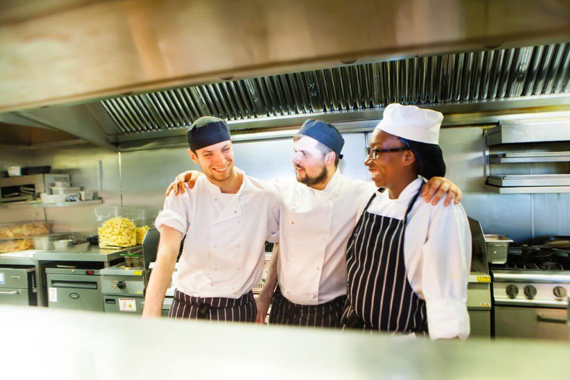 chefs arms around each other in kitchen