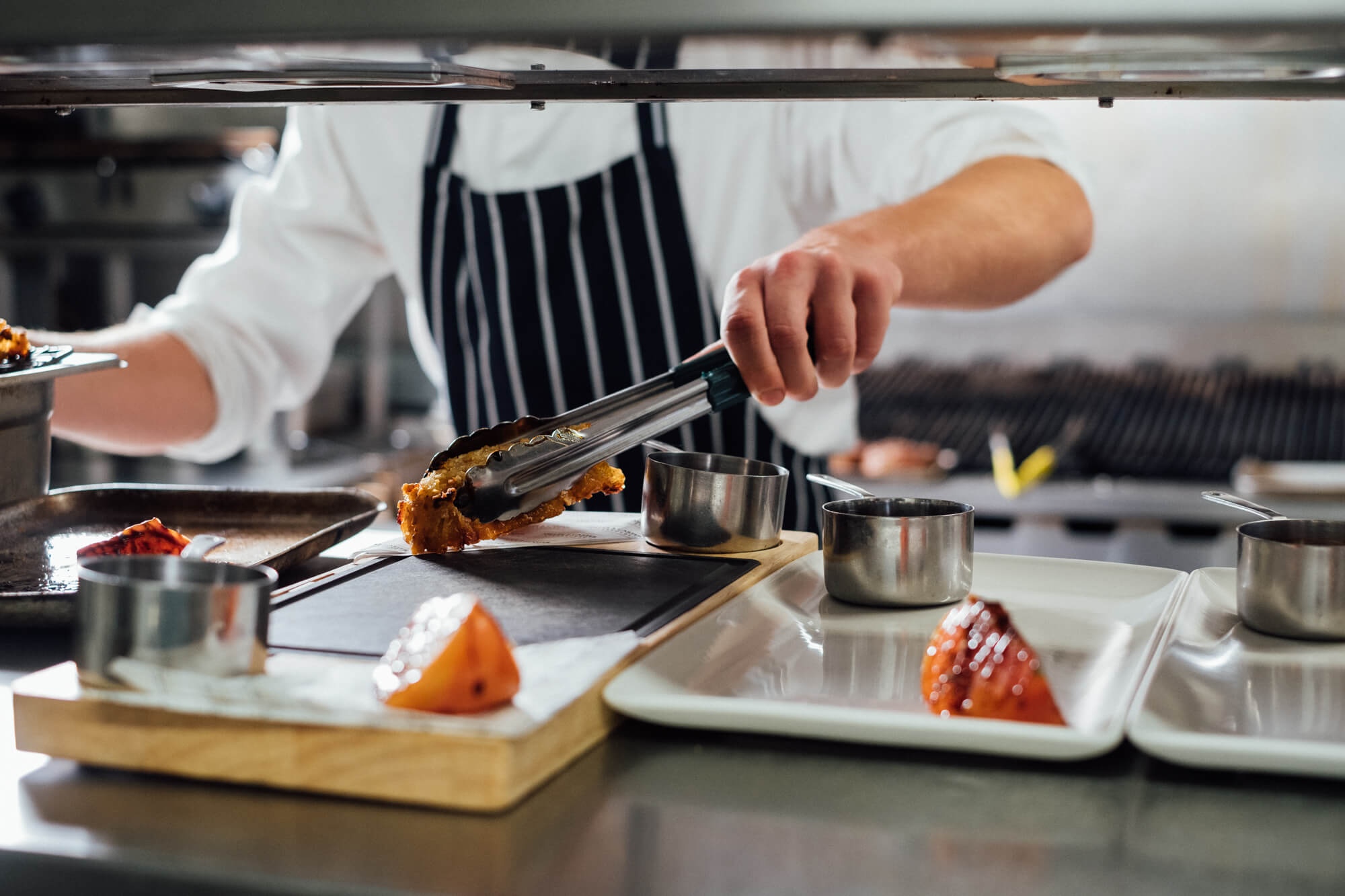 chef plating hot food in restaurant kitchen