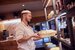A harvester kitchen assistant smiling while carrying a bread basket