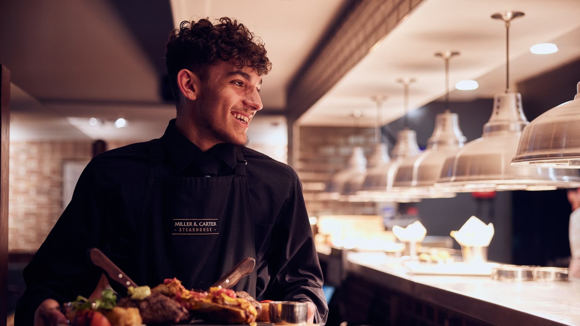 hospitality with heart - waiter smiling whilst serving food 