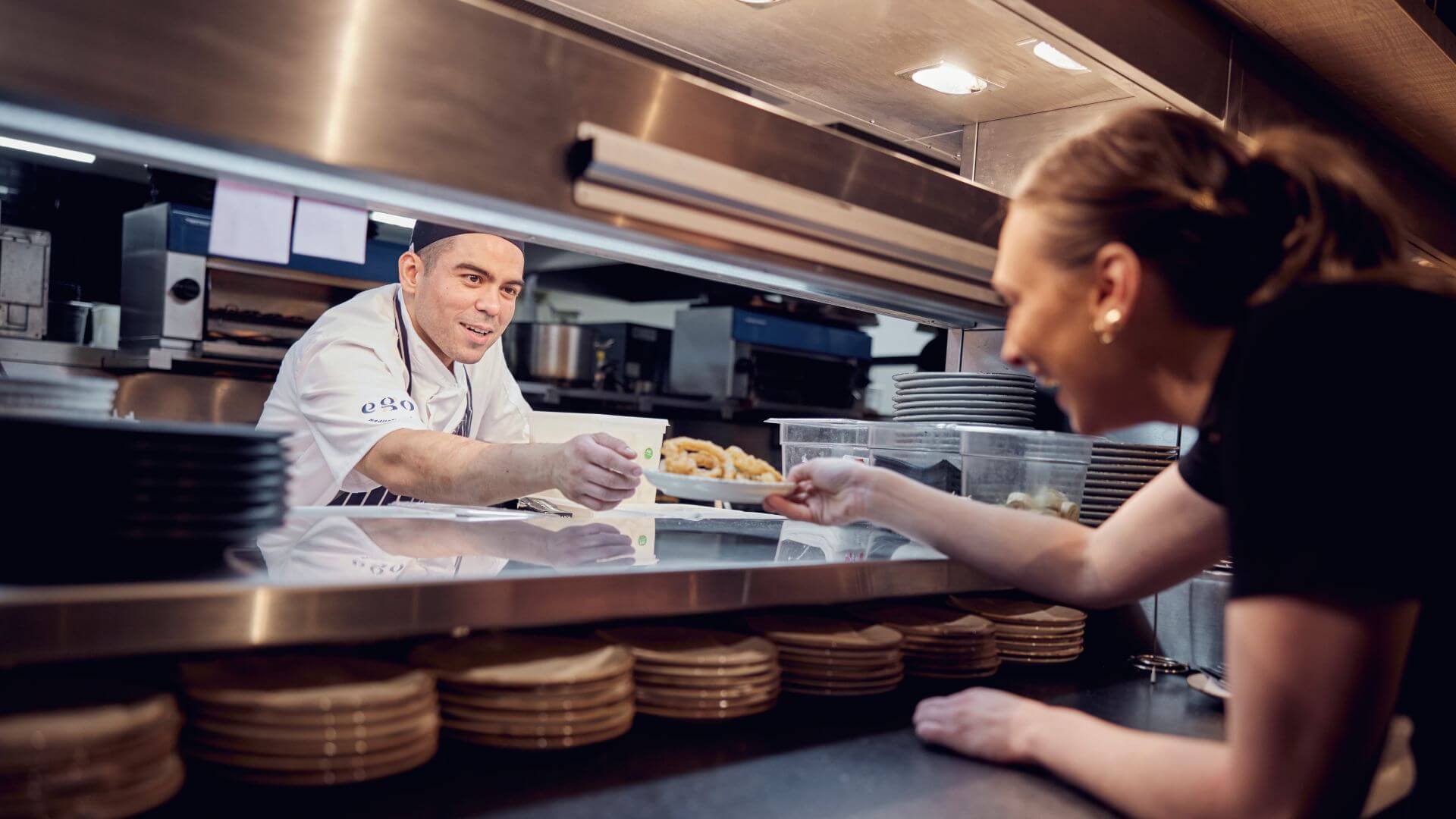 image of ego employees in the kitchen passing plate of food 