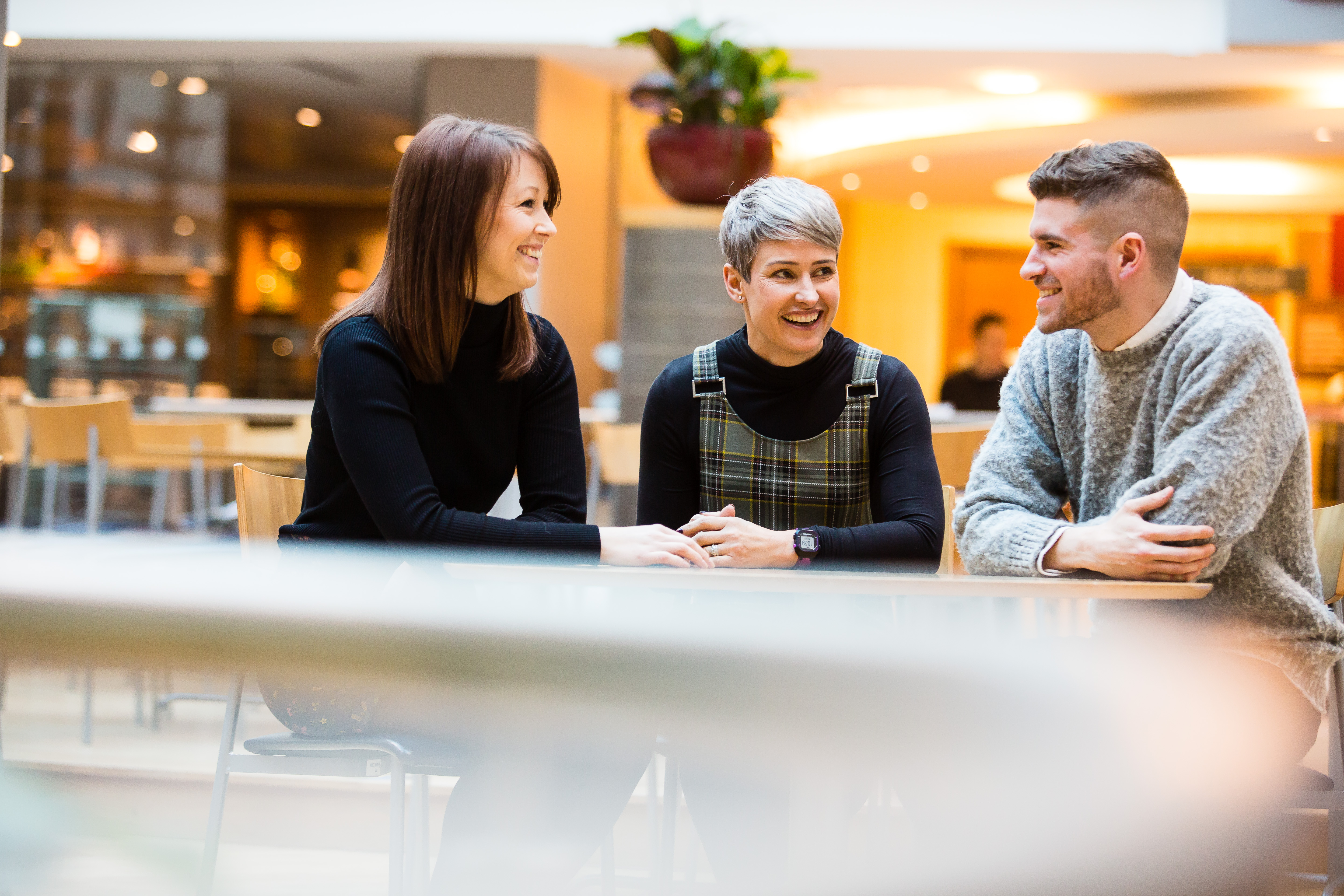 three people sitting at a table laughing