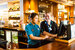 An assistant manager with a staff member smiling as they operate a till