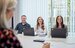 image of graduate and team in a meeting smiling with laptops on desk 