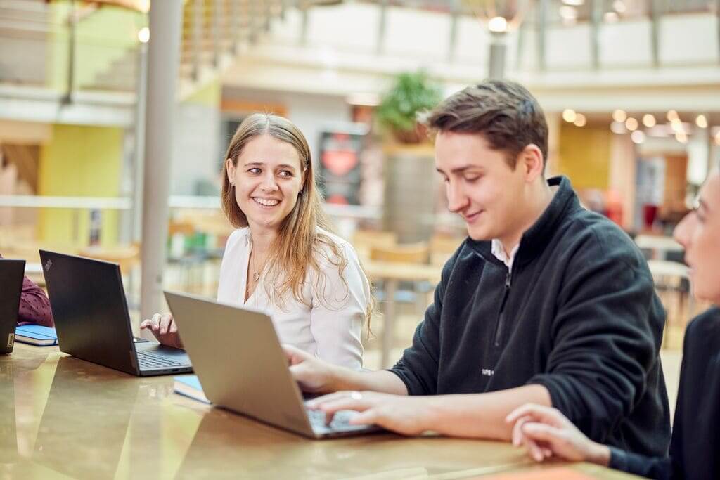 image of property undergraduate sitting at desk laughing with colleagues 