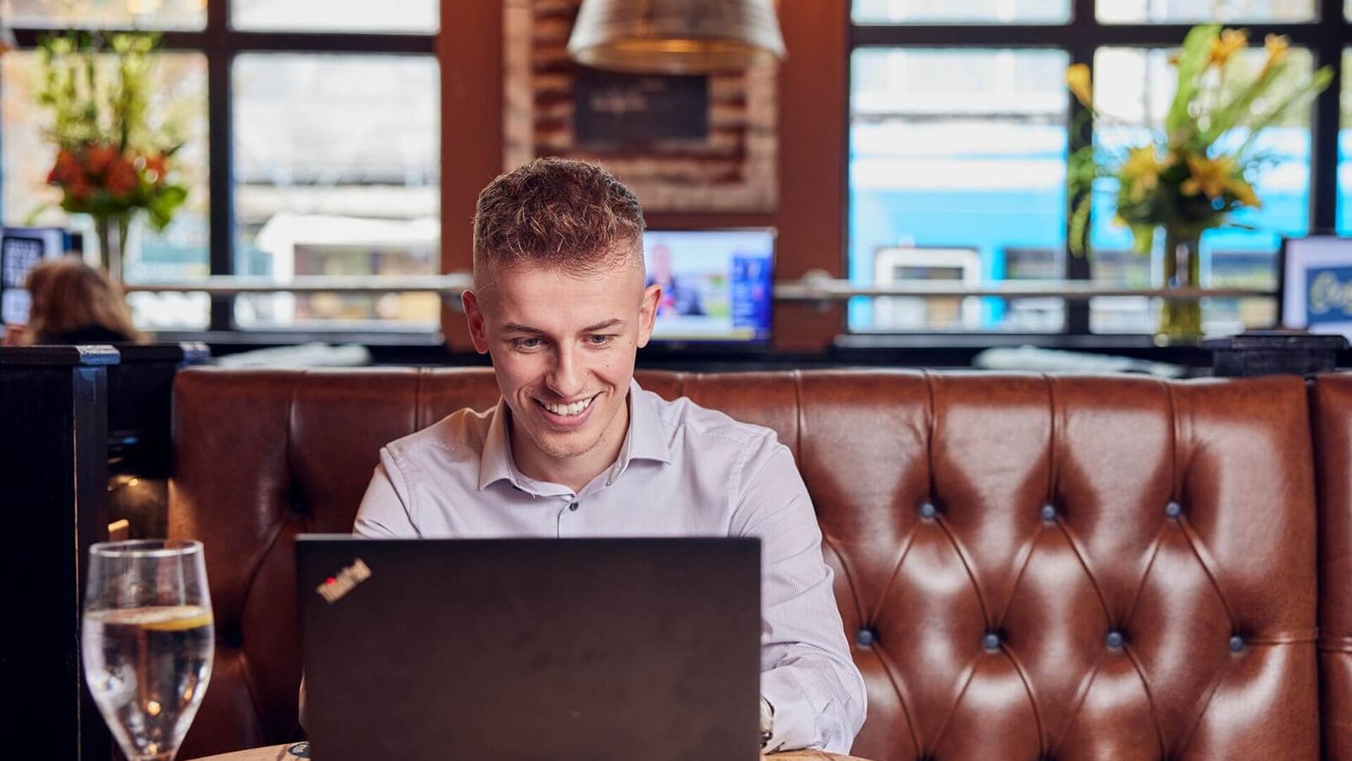 graduate sitting at restaurant working with a smile