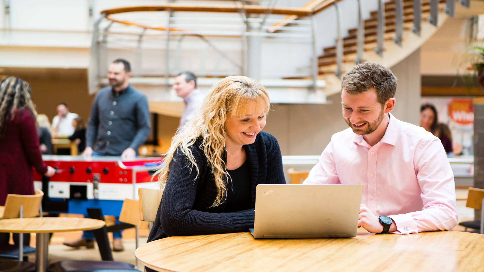 Male and female sitting at table looking at laptop in office