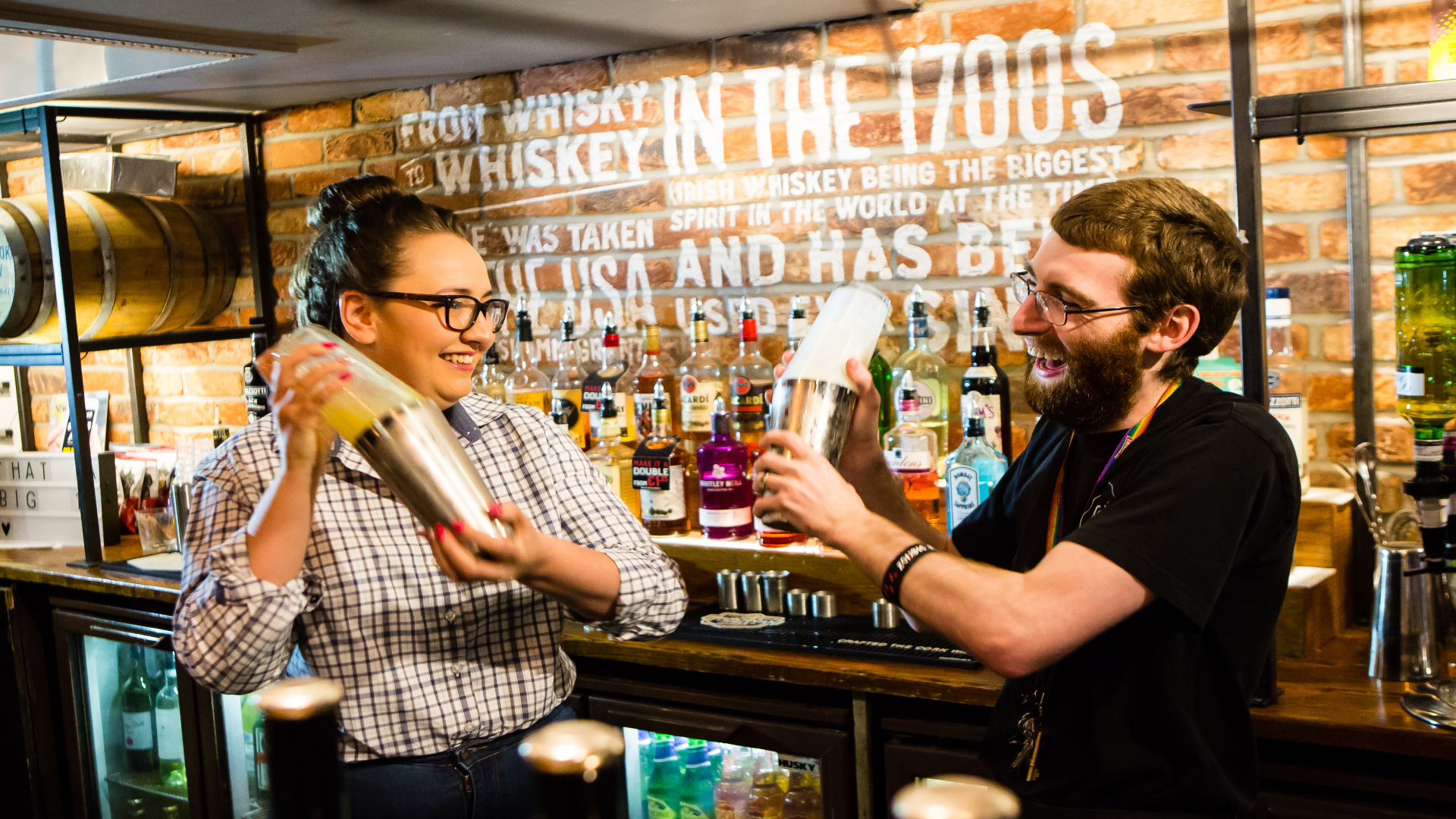 2 bartenders shaking cocktails behind bar