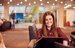apprentice sitting on sofa working on laptop smiling 