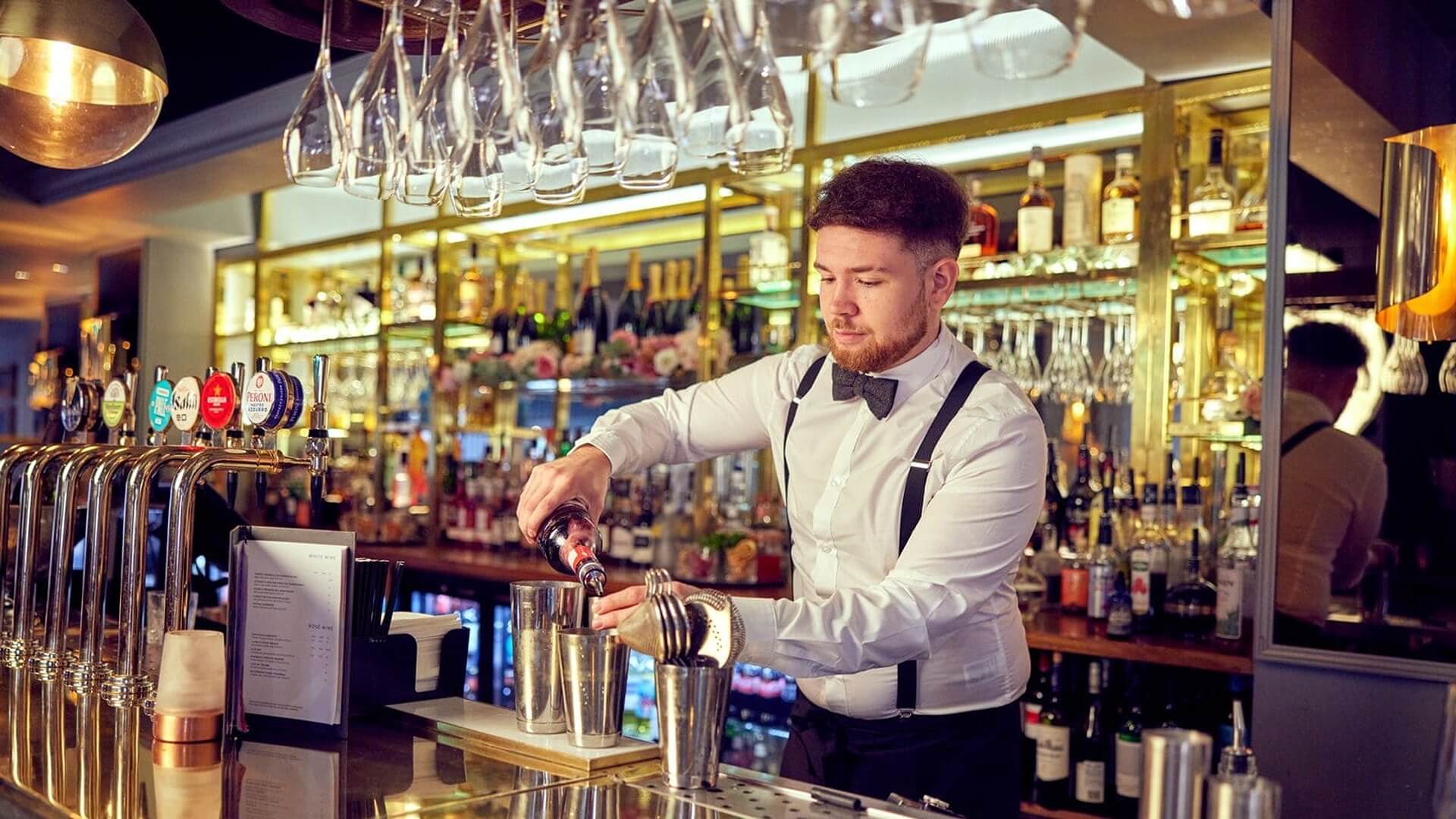 student pouring drinks behind bar at M&B 