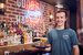 part time bartender holding some drinks and smiling 