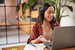 Smiling woman in collections job with headphones talking while attending a meeting online using laptop.