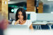 woman in a white top working in an office looking at a computer screen