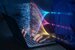 hands typing on a laptop with string of code illuminating above