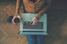 man with laptop with coffee sitting on floor 
