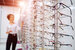 optician standing next to rows of glasses