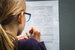 view of young girl with glasses from behind working on school work