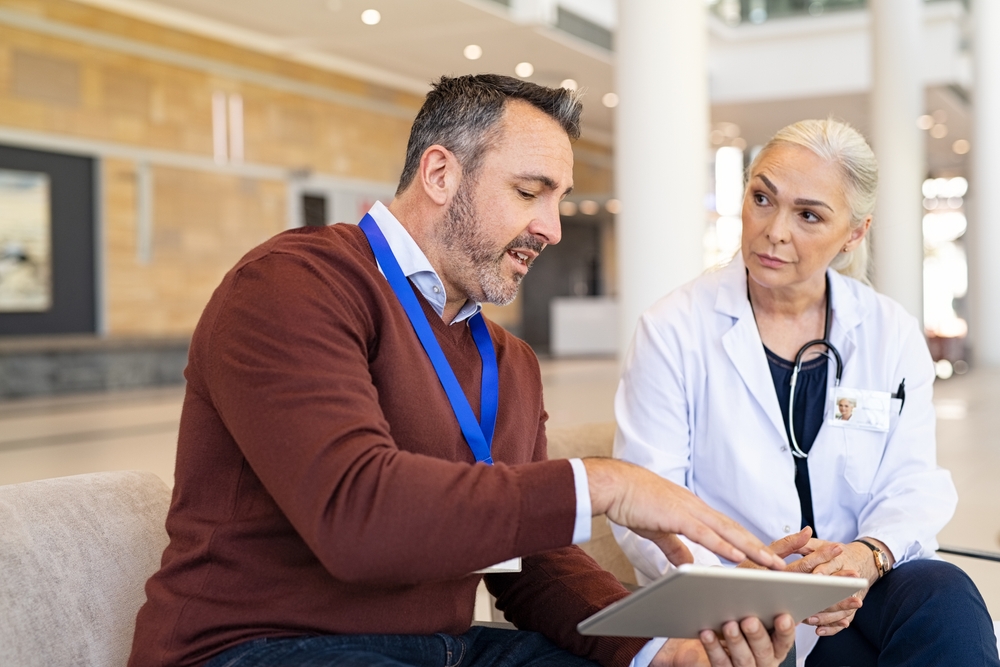 women in medical coat and stethoscope sat on sofa consulting a male medical sales rep