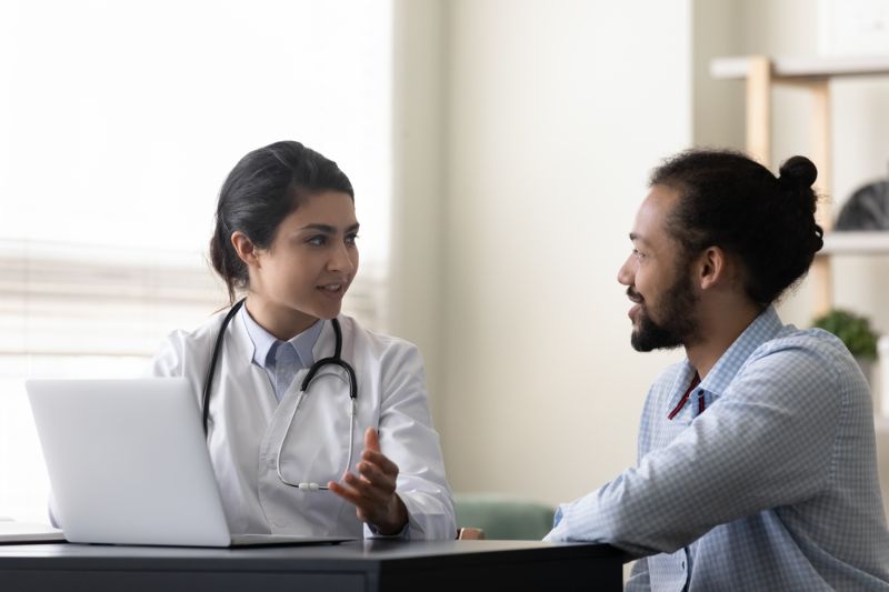 women in white lab coat and stethoscope talking to a man