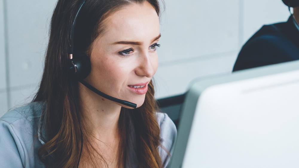 woman wearing a phone headset looking at a computer screen