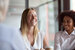 Smiling millennial lady having fun with diverse corporate team people engaged in talking at work