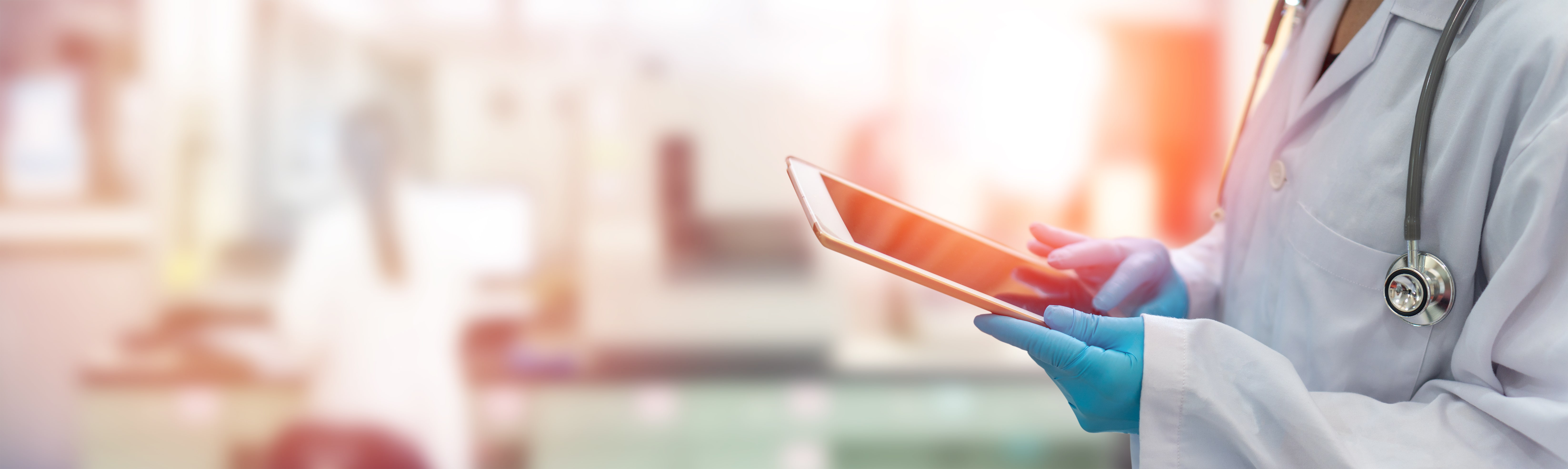 Healthcare professional medical doctor with stethoscope hand using tablet online with blurred background.