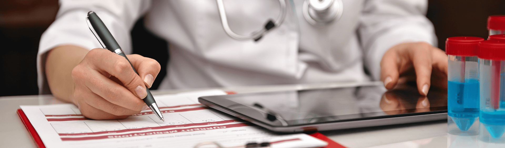 Medical professional writing notes and using tablet