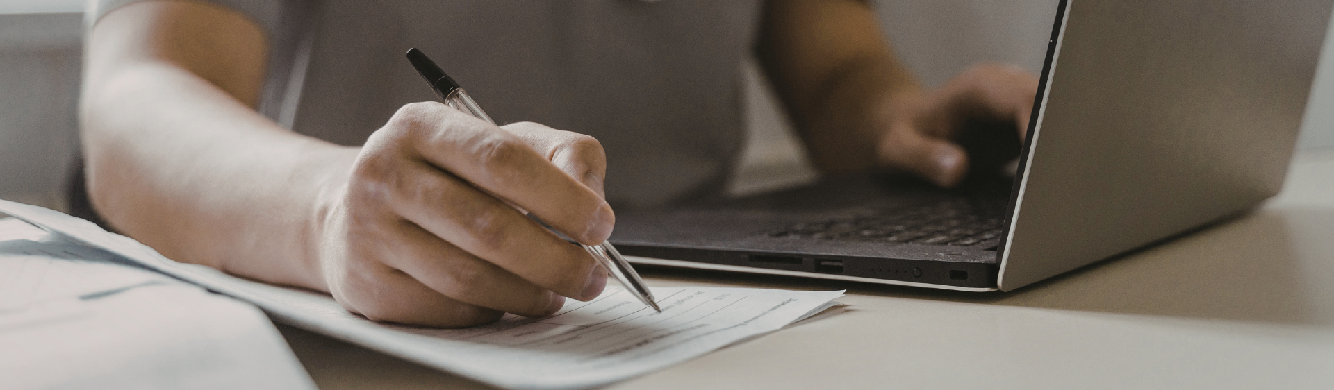 Person using laptop and writing notes