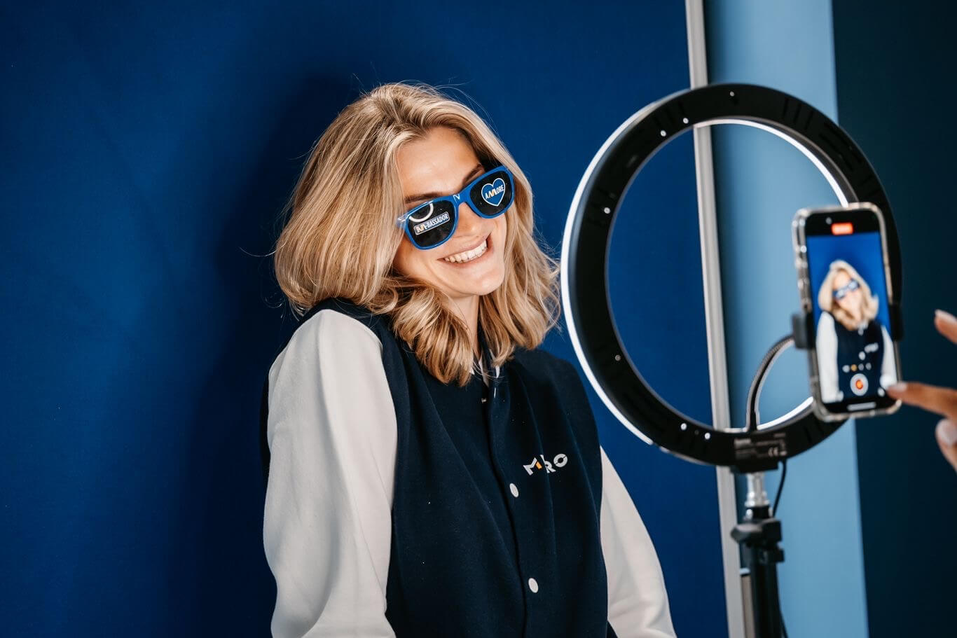 woman in front of a ring light being filmed on a phone
