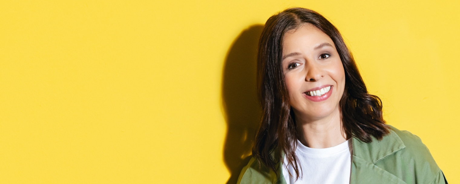 a woman smiling against a yellow backdrop