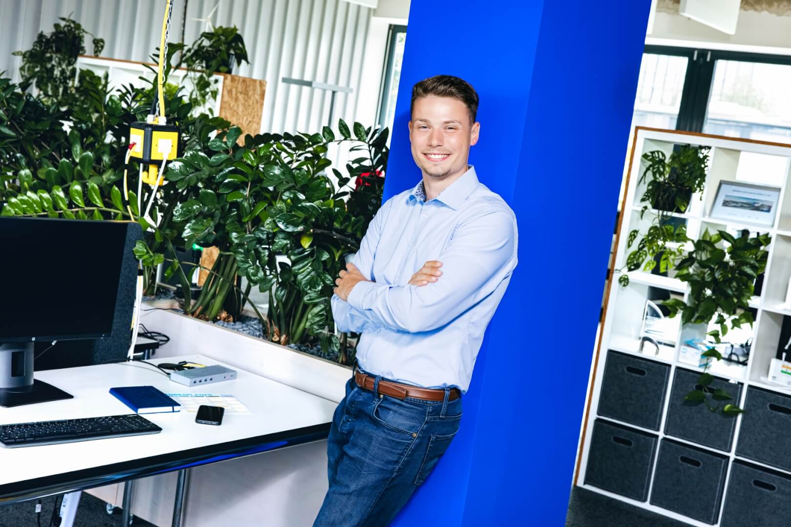 a working professional in a modern working space leaning against a pillar